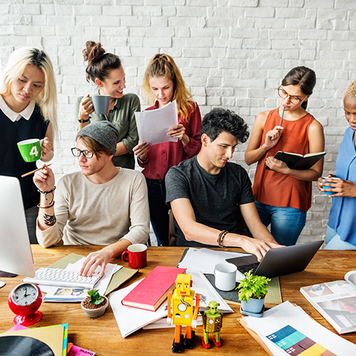 A group of people sitting around a table with laptops.